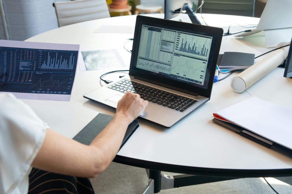 Business person evaluating financial charts on a laptop in a modern office setting.